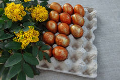在一个展台上画上棕色和金色的复活节彩蛋, 桌面上有一束鲜花和绿叶