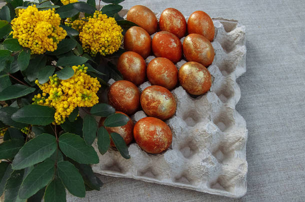 在一个展台上画上棕色和金色的复活节彩蛋, 桌面上有一束鲜花和绿叶