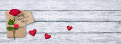 在破旧的木板和文字复制空间的背景下, 可以看到情人节卡片的顶视图, 上面有天鹅绒般的心、礼物和红玫瑰