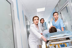 担心的医生和护士运输无意识病人在轮床