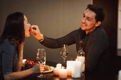 美丽的激情夫妇在家里有一个浪漫的烛光晚餐, 互相喂食
