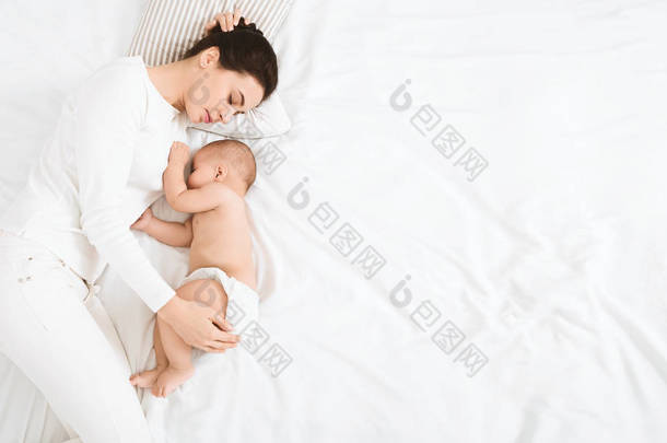 年轻的妈妈和她可爱的宝宝睡在床上