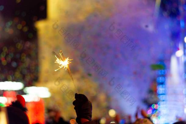 在主广场庆祝新年.很多烟或雾，<strong>灯光</strong>，敬礼和意大利面。模糊的彩色背景。孟加拉火在手，手套在前景。音乐会<strong>现场</strong>，画面右方有蓝光.
