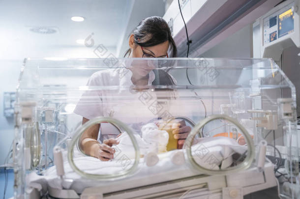 女医生在孵化器中检查新生儿