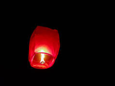 天空灯笼照明由一双手拿着纸热气球在黑色背景