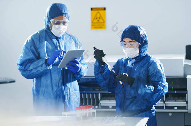 严重集中的多民族临床科学家在生物危害西装和口罩工作与血液样本，而在实验室进行研究