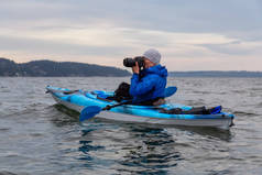 冒险摄影师用他的相机在海洋中的皮划艇拍照。拍摄于加拿大不列颠哥伦比亚省西温哥华马蹄湾附近的豪湾.