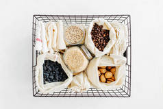 坚果、干果和果子在生态棉袋和玻璃罐在厨房的白色桌子上