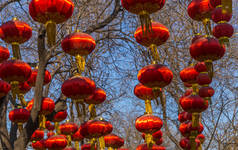 在中国北京，一条以蓝天为背景的街道上，几盏红色的中国灯笼