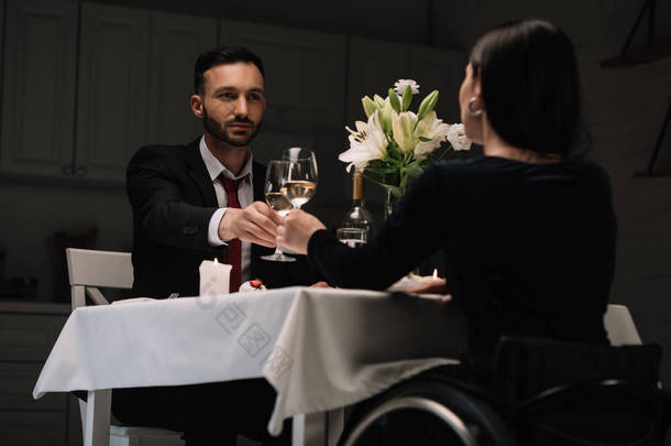 在浪漫晚餐中残疾年轻女子与英俊男友一起喝红酒的背景