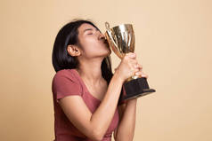 成功的年轻亚洲女人拿着亲吻奖杯.