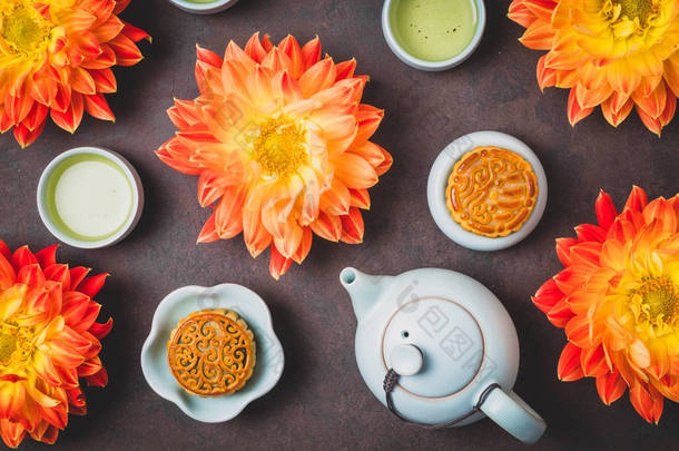 月饼在新鲜的橙色大丽<strong>花</strong>，一个蓝色的茶壶和一杯绿茶在棕色的背景。中国<strong>中秋</strong>节食品.