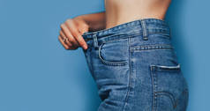瘦女人的身体与宽松的裤子牛仔裤，轻重量的身体与宽松的衣服，苗条和健康的身体低脂肪的概念