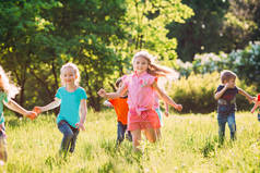 在阳光明媚的夏日，一群身穿休闲装的孩子、朋友、男孩和女孩在公园里奔跑 .