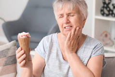 有敏感牙齿和冷冰淇淋的老年妇女在家里