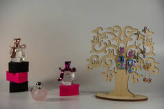 木制支架，三对长耳环，黑色和粉红色的海绵，白色背景上带有芬芳香水的小瓶子.