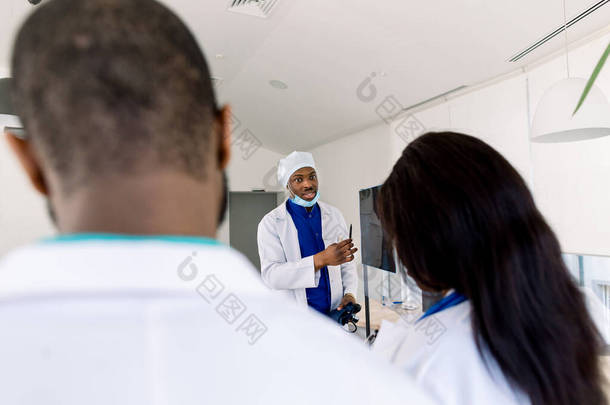 医生团队与X光。 保健。 放射科。 在医院检查X光报告的专家小组医生。 站在董事会旁边的非洲男医生