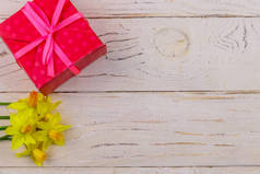 礼物盒和白色木制背景的黄色水仙花。 情人节、妇女节、母亲节及生日的概念