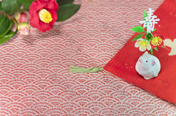日本人的贺卡上有一朵叫做冬日玫瑰的小白鼠花和一个可爱的小白鼠形象，这是它2020年的时候穿上的<strong>红色布</strong>上的，上面装饰着日本人的Kotobuki表意文字，意思是长寿.