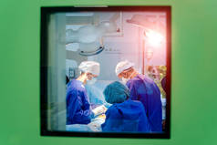 从窗户往手术室看. 使用医疗设备进行外科手术的过程。 一组外科医生带着手术器械在手术室里. 医疗背景.