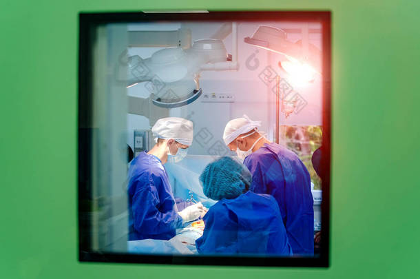 从窗户往手术室看. 使用医疗设备<strong>进行</strong>外科手术的过程。 一组外科医生带着手术器械在手术室里. 医疗背景.