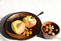 素食，饮食食物。 桌上放着一盘苹果，上面烤着奶酪、蜂蜜、坚果和葡萄干.