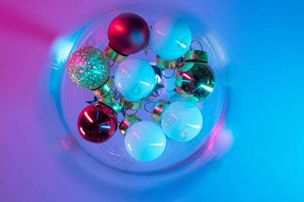 用粉色和蓝色霓虹灯装饰圣诞树球的空酒杯 