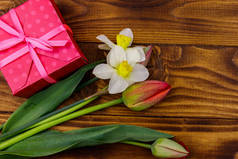 礼物盒和一束红色郁金香和水仙花，木制背景。 情人节、妇女节、母亲节和生日的概念。 顶部视图，复制空间