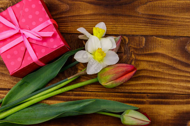 礼物盒和一束红色郁金香和水仙花，木制背景。 情人节、<strong>妇女节</strong>、<strong>母亲节</strong>和生日的概念。 顶部视图，复制空间