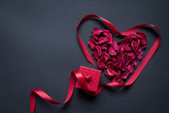 红花瓣丝带呈心形，红礼盒呈黑色底色，祝贺你