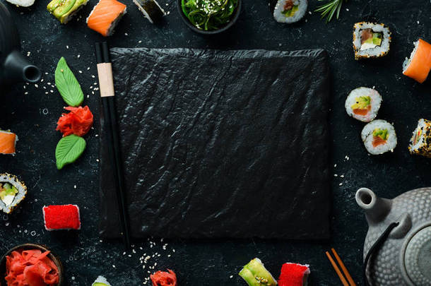 一套寿司卷与生姜，芥末和酱油在黑色的石头背景。 日本传统烹饪。 顶部视图。 乡村风格.