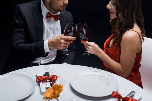 雅致情侣与红酒在与黑色隔离的餐桌旁的侧视图