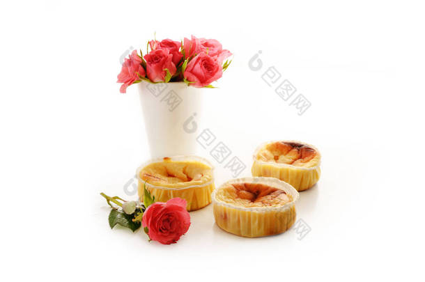 自制的小凝块糕点或松饼和一个粉色玫瑰花瓶，白色背景上有阴影，复制空间