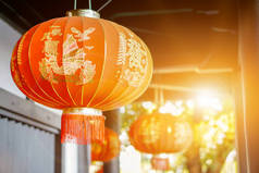美丽的中国装饰红色灯笼挂在古寺天花板上，背景模糊不清，阳光灿烂。 2.中文灯笼上的字母在英语中是吉祥的恭维话.