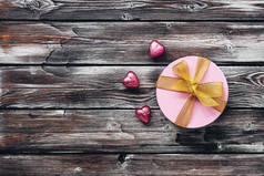 粉红礼盒和巧克力的心在旧的破旧木制背景的铝箔。 俯瞰，平铺。 假日贺卡.