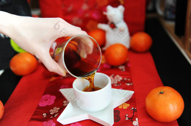 中国咖啡仍然有效。 把咖啡从卡拉菲倒入杯中。 传统面料图案。 白老鼠，橘子