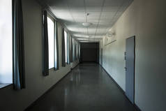 黑暗的学校弯曲的走廊，有丑陋的绿色窗帘和黄色的墙壁，时钟显示上午9点20分.