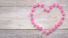 心脏来自木制背景上的小粉色玫瑰