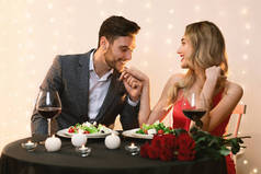 浪漫美丽的情侣在餐馆吃饭，可爱的男人亲吻女友的手