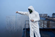 身穿防护服的科学家们正在高楼、污染区顶部的玻璃瓶中使用蓝色试剂进行研究