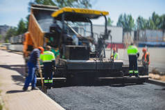 柏油摊铺机及蒸汽压路机在道路建造及修葺工程、铺沥青及铺路过程中，工人在新的道路建筑地盘上工作，放置一层