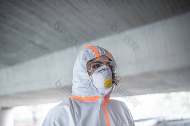 穿着防护服和呼吸器站在室外的妇女，验尸官的概念.