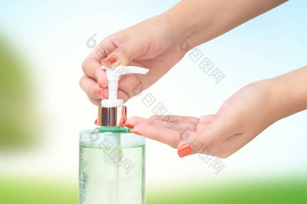 手部使用洗手手部清洁剂凝胶泵分配器模糊的绿色自然背景.