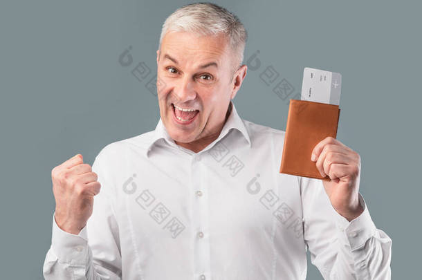 Happy senior man holding tickets and his passport