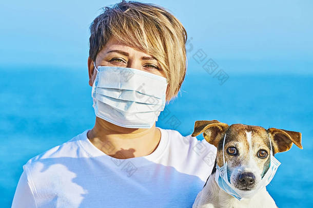 戴防护面罩的女人还有戴着医疗面罩的狗中国的考利氏病COVID-19对宠物来说是危险的，皮的主人避免亲吻他们的宠物概念