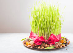 诺鲁孜节快乐。庆祝各种干果，坚果，种子，绿色青草小麦的颜色背景，复制空间顶部视图