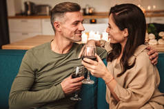 图为一对充满热情的情侣在家中享用浪漫烛光晚餐时用眼镜喝红酒的情景