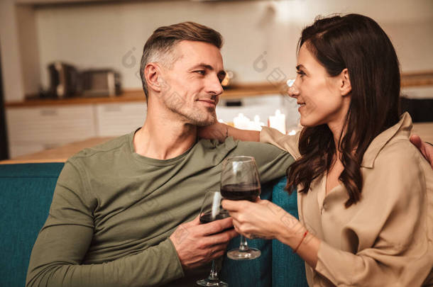 图为一对充满热情的情侣在家中享用浪漫烛光晚餐时用眼镜喝红酒的<strong>情景</strong>