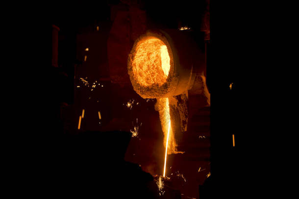 冶炼在工厂工作.场景。在冶炼厂,合金喷出,火花向不同<strong>方向</strong>喷出.明亮的热流合金流和闪光