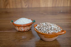 墨西哥风格的粘土容器，有米粒和豆子放在木板上